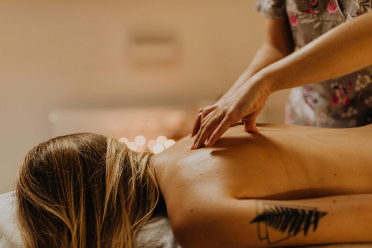 Rückenmassage mit Öl, Kerzen im Hintergrund